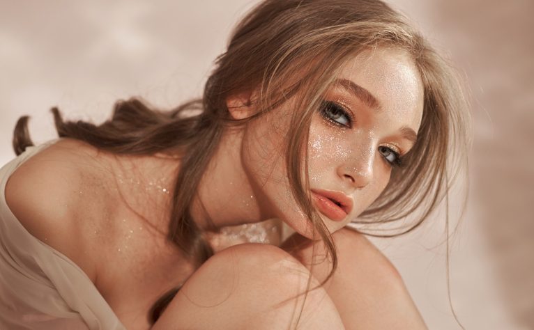 Beautiful sexy woman sitting on the floor, cosmetics and makeup on the girl face and body